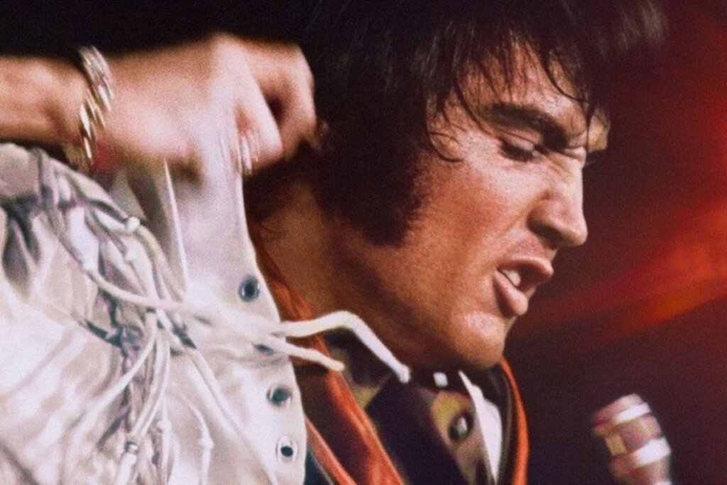 Elvis Presley cantando e usando uma roupa branca em cena do documentário "EPIC: Elvis Presley In Concert"
