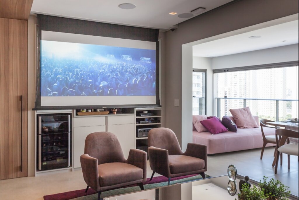Sala de estar com home theater, poltronas voltadas para a tela e bar integrado ao móvel com adega e equipamentos