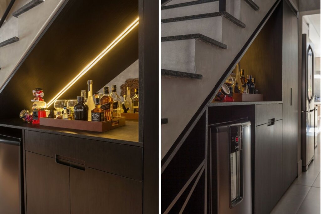 Bar instalado sob a escada com marcenaria planejada, adega compacta e bandeja com garrafas e copos