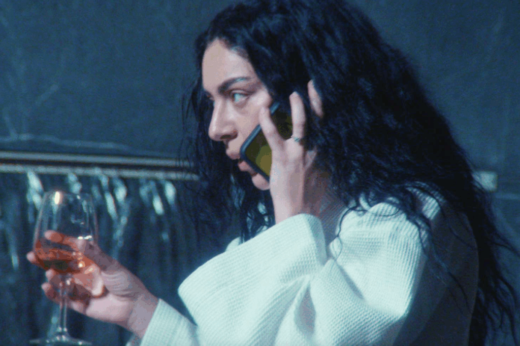 Mulher falando ao celular enquanto segura uma taça de bebida em ambiente com luz azulada