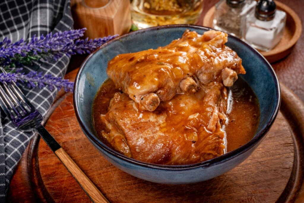 Costela suína ao molho picante servida em tigela funda de cerâmica em cima de mesa de madeira
