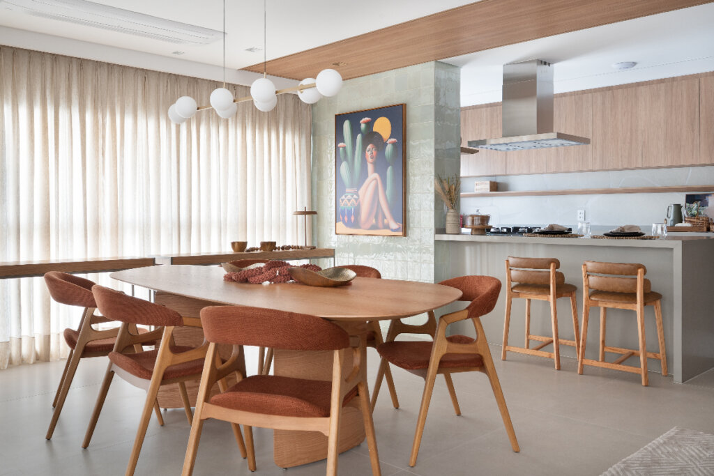 imagem de sala de jantar com mesa grande de madeira com cadeiras estofadas e quadro colorido ao fundo