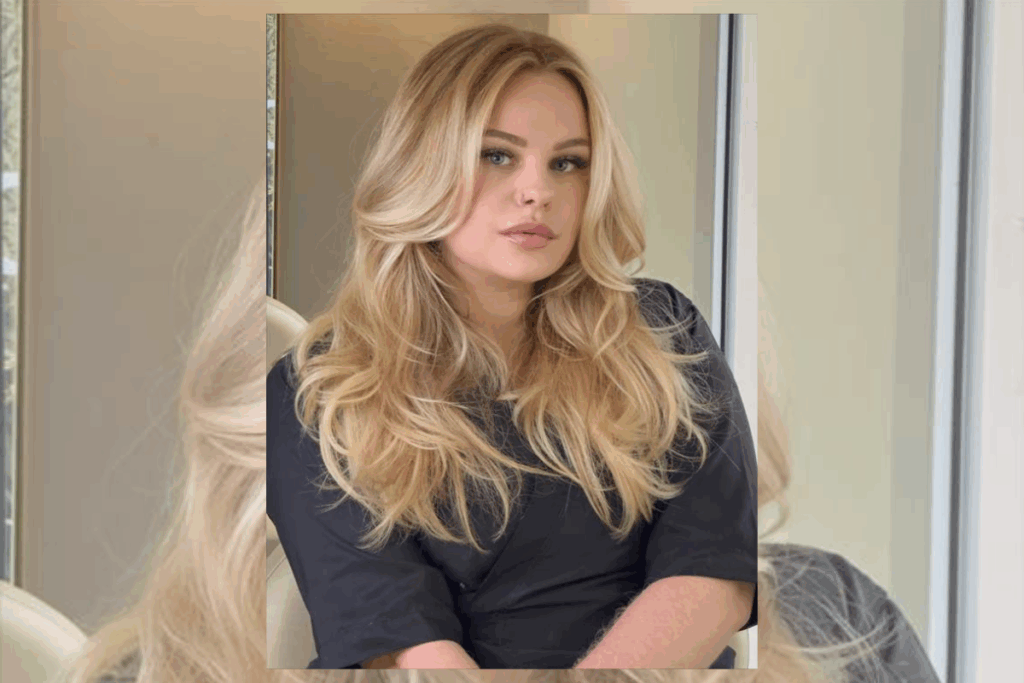 Mulher com o cabelo loiro ondulado, usando camiseta preta