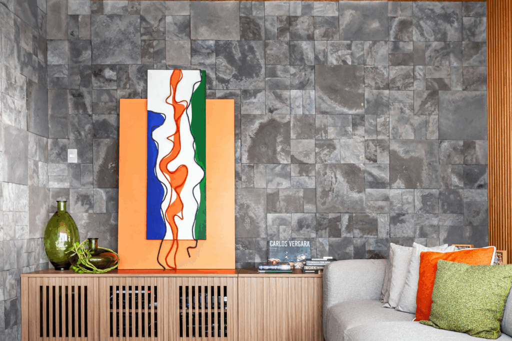 Sala de estar com sofá branco, móvel em madeira e quadro em tons de laranja, azul, branco e verde