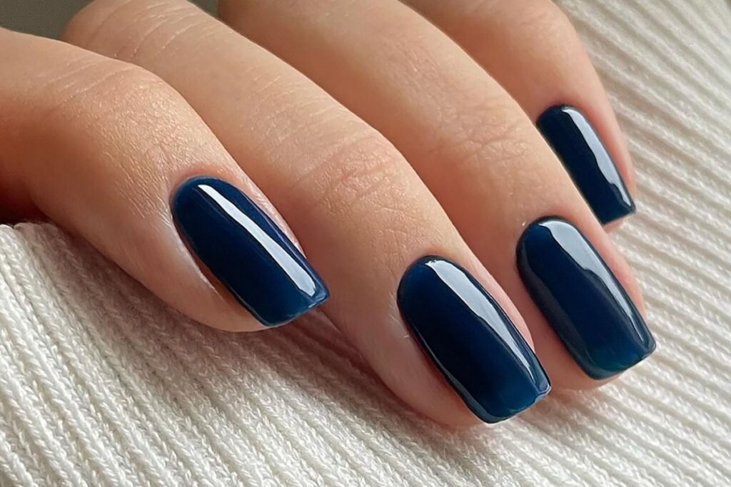 mão feminina com unhas em tom de azul intenso